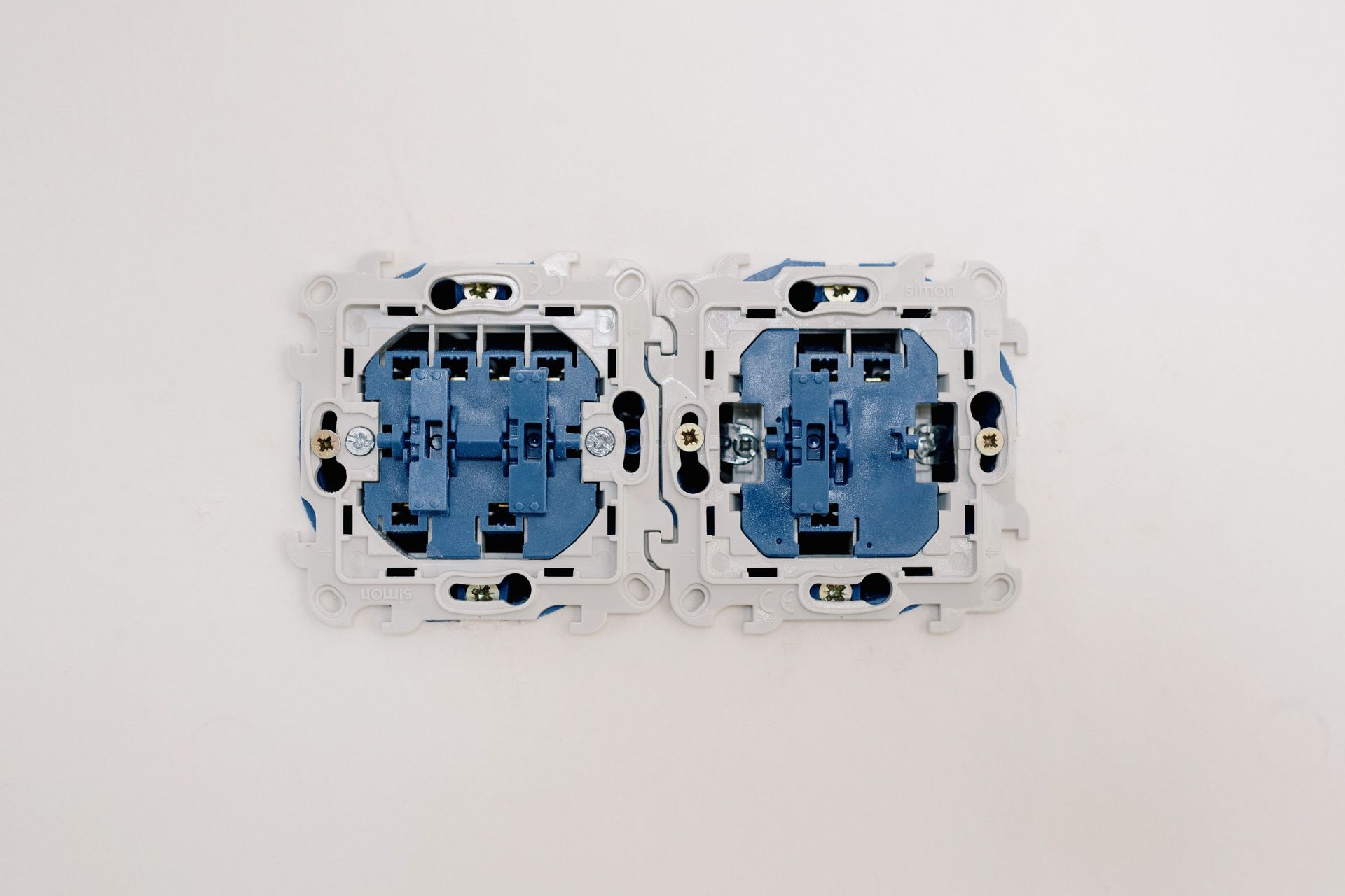 Two blue electrical wall switches mounted side by side on a white surface