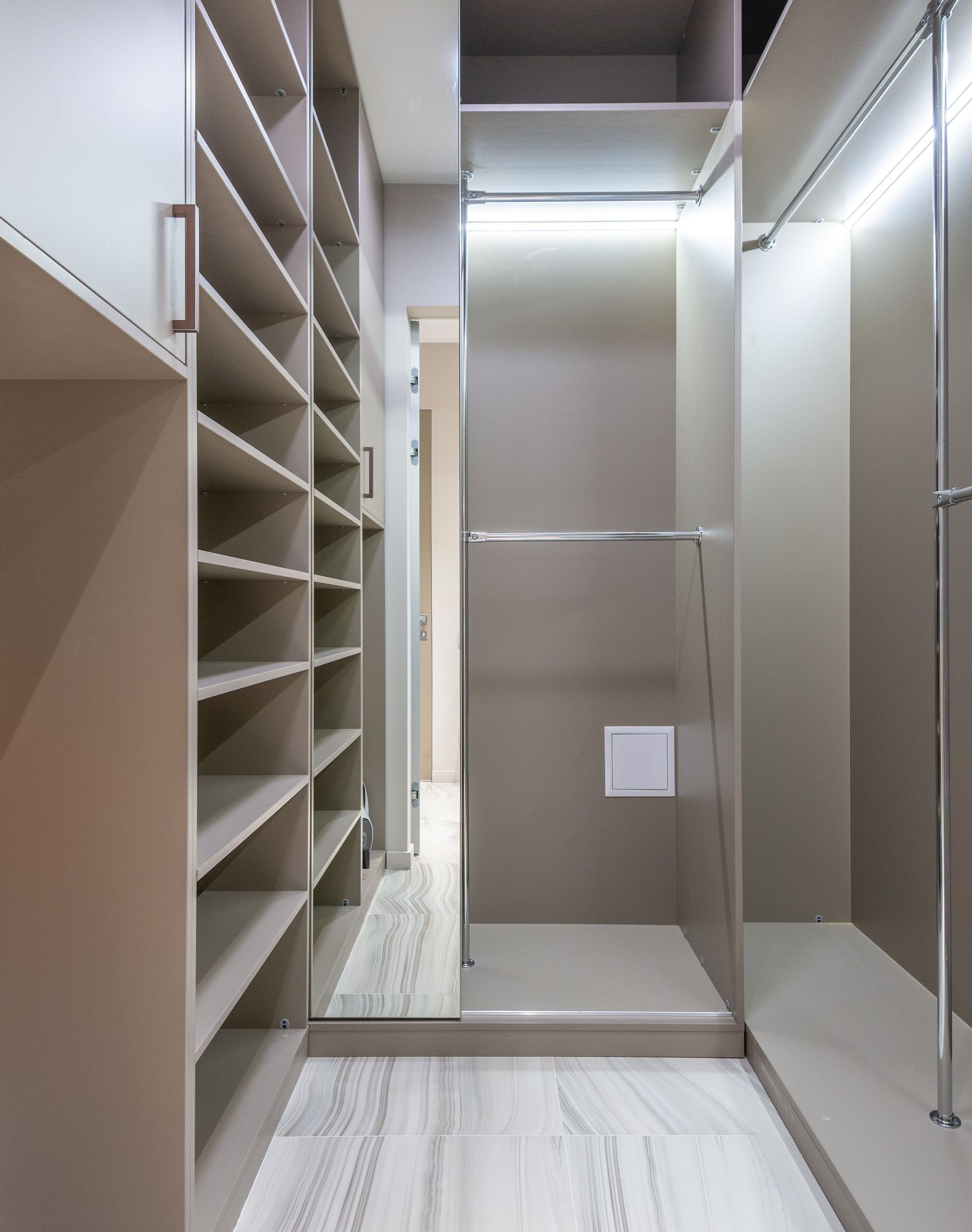 Narrow walk-in closet with shelves on the left, mirrored doors on the right, and a frosted glass door at the back.