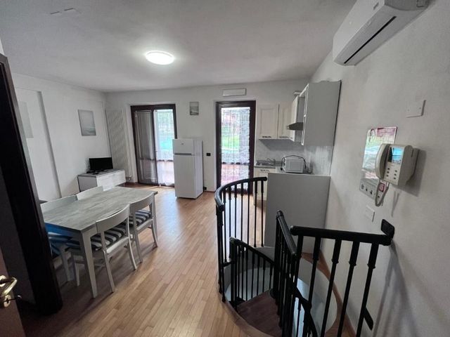 Interno di un piccolo appartamento con cucina, zona pranzo e scala a chiocciola.