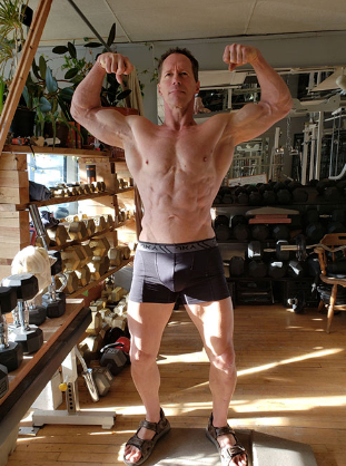 A man is flexing his muscles in a gym.