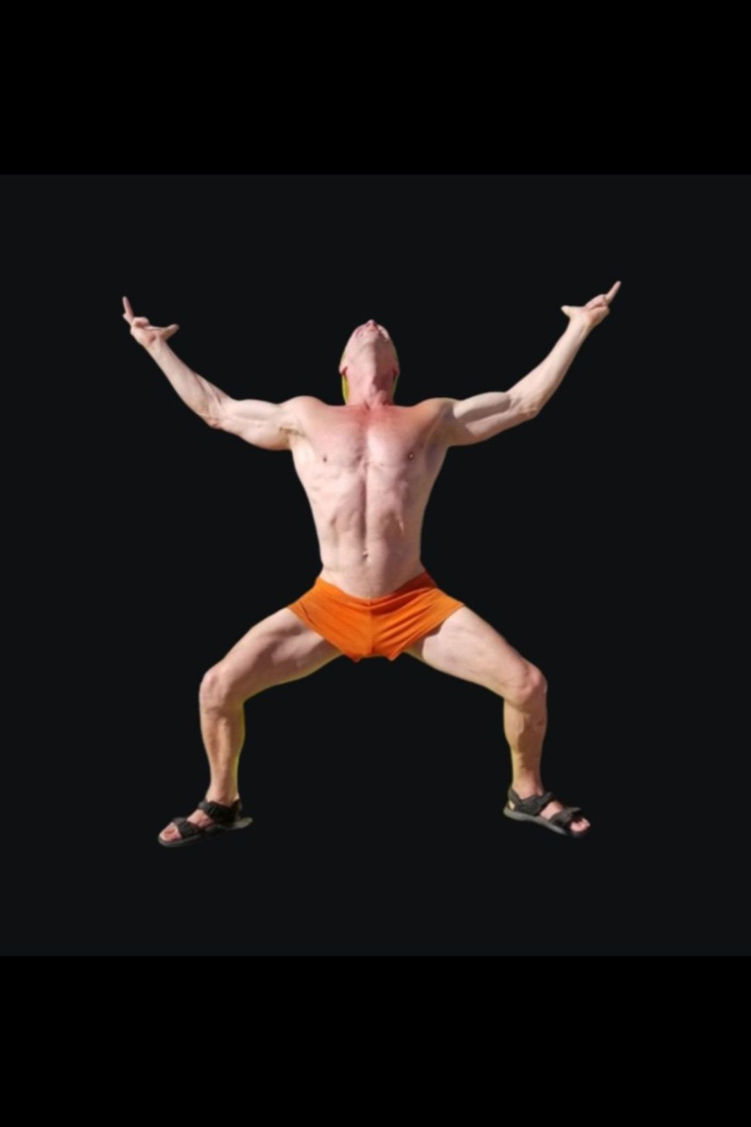 A shirtless man in orange shorts is dancing with his arms outstretched.