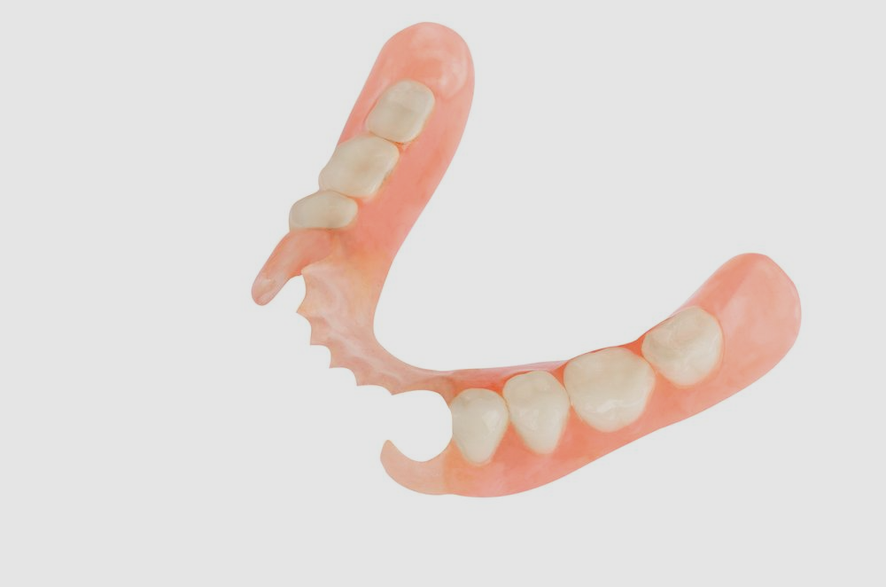 A close up of a denture with teeth on a white background.