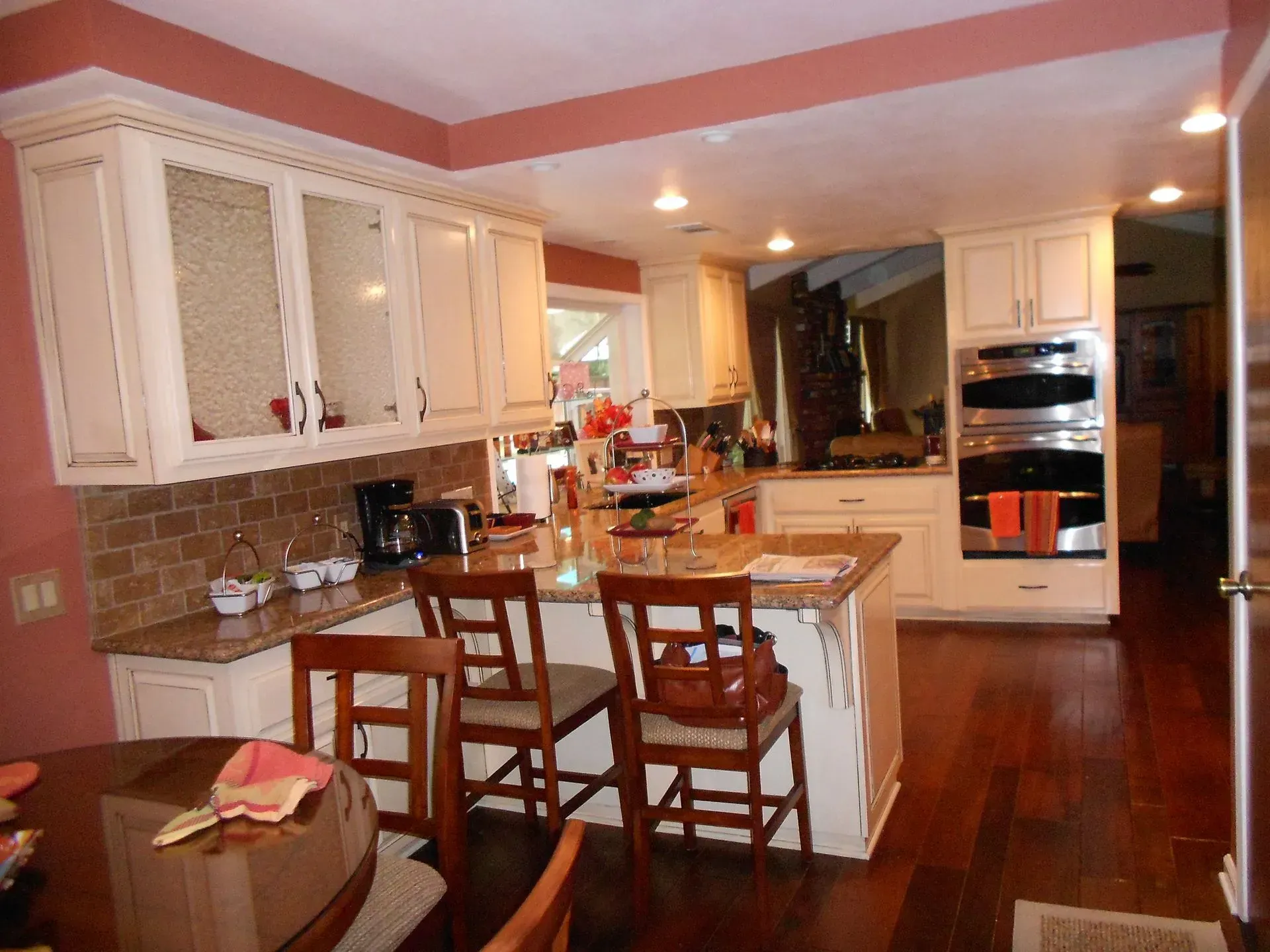 Spacious kitchen with white cabinets, wood floors, island seating, and warm recessed lighting