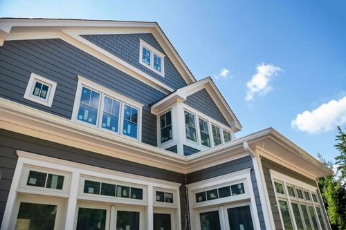 Blue-gray house with white trim and large windows under a bright blue sky