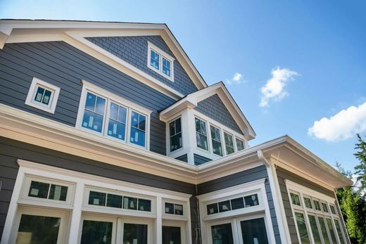 Blue-gray house with white trim and large windows under a bright blue sky