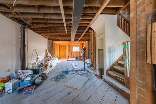 Unfinished room under renovation with exposed beams, tools, and debris on the floor