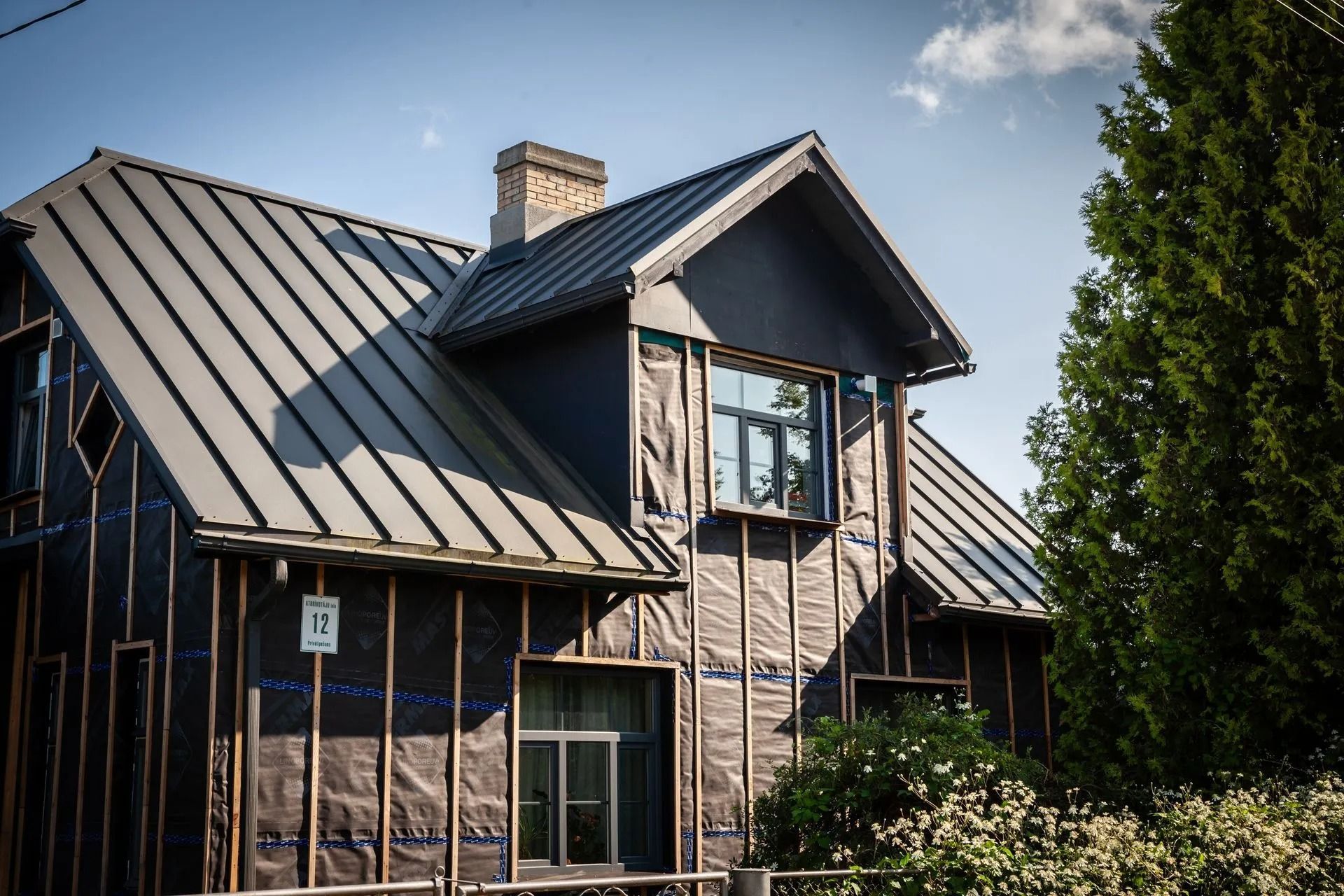Modern house with dark metal roof and wood siding under a blue sky