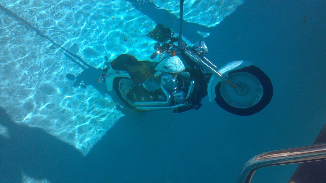 A motorcycle is floating underwater in a swimming pool.
