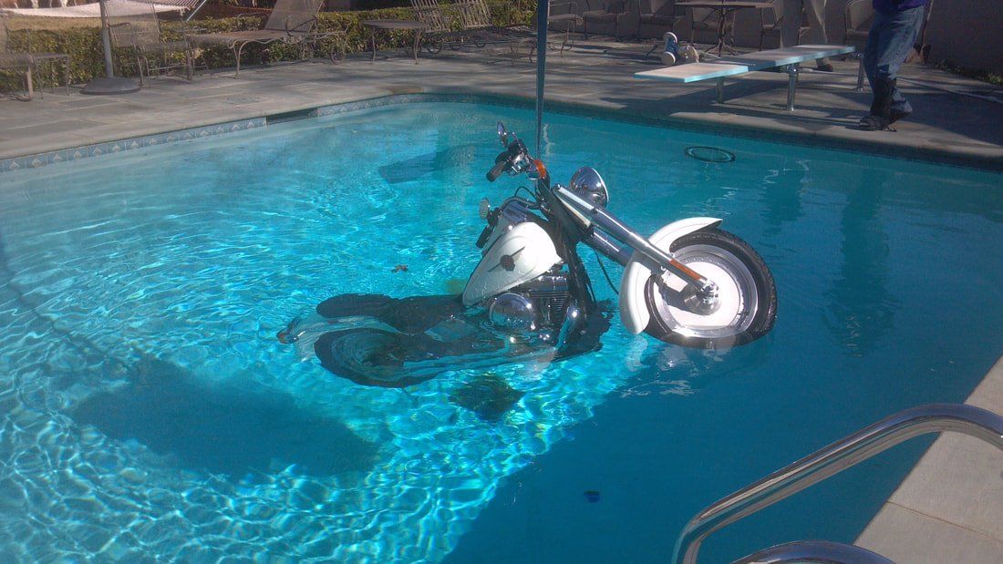 A motorcycle is floating in a swimming pool.