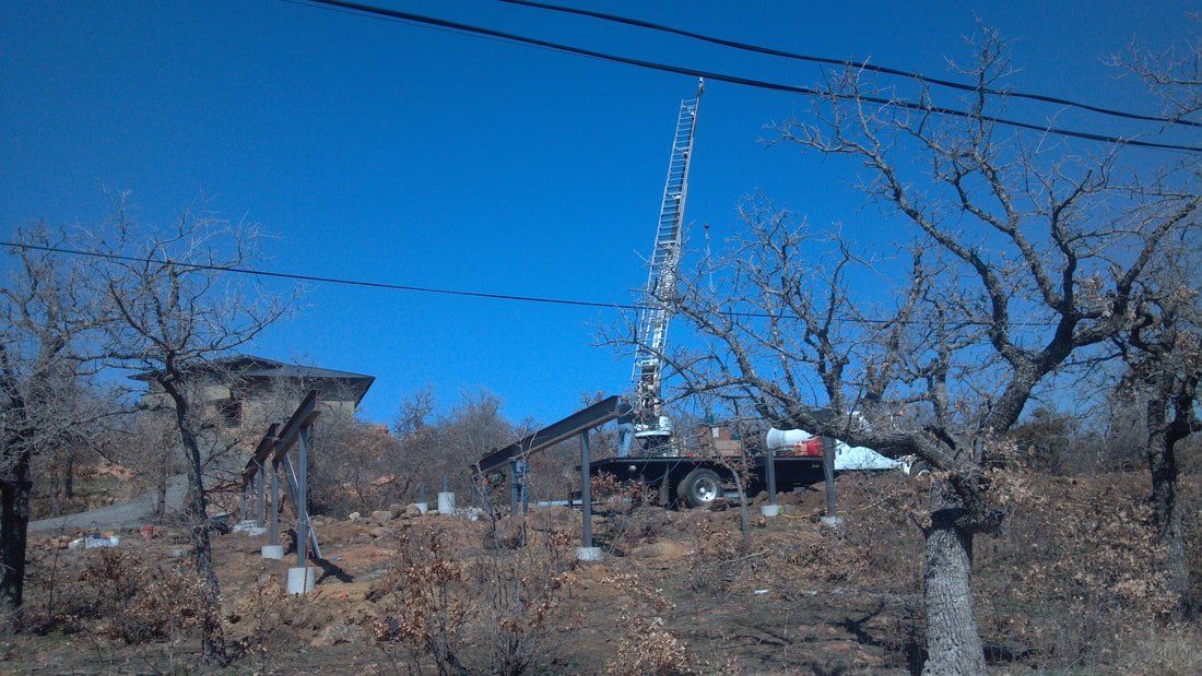 A crane is sitting in the middle of a field next to a house.