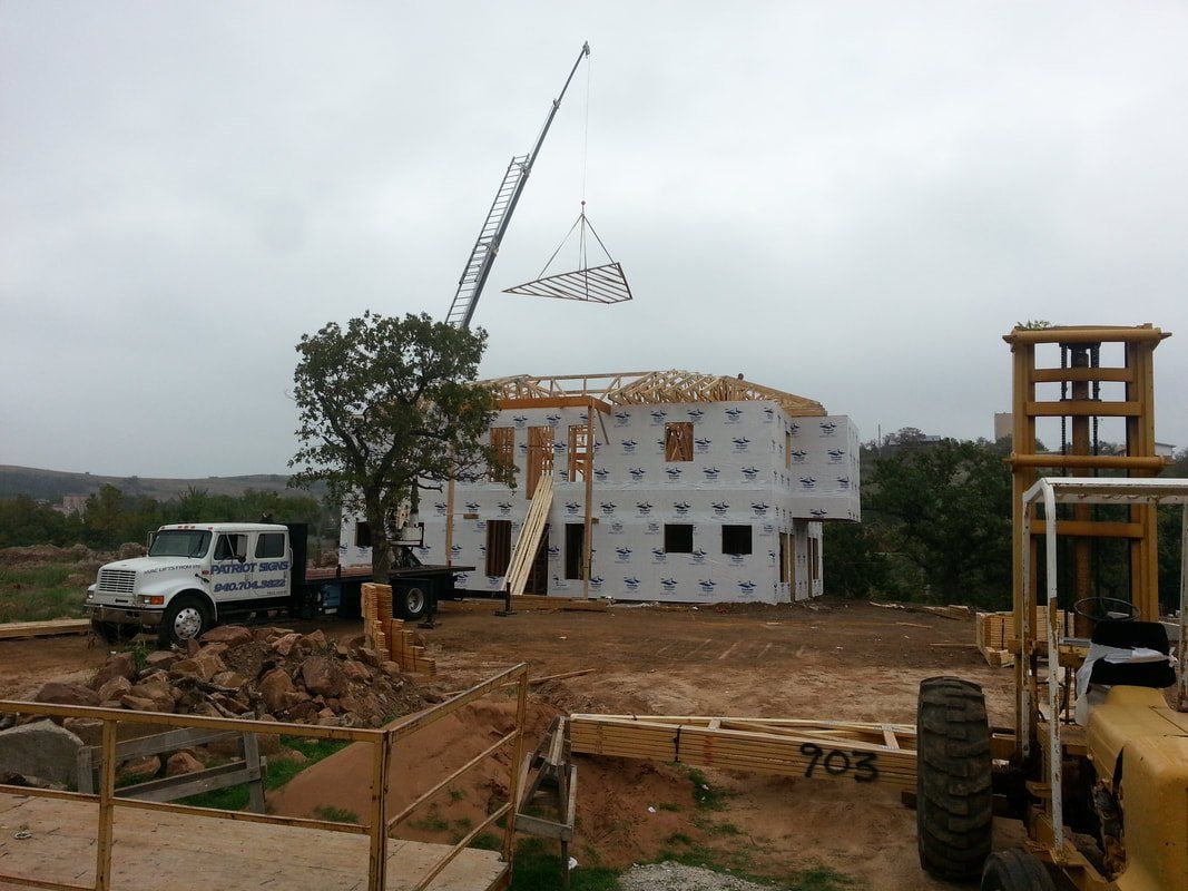 A crane is lifting a piece of wood over a house under construction