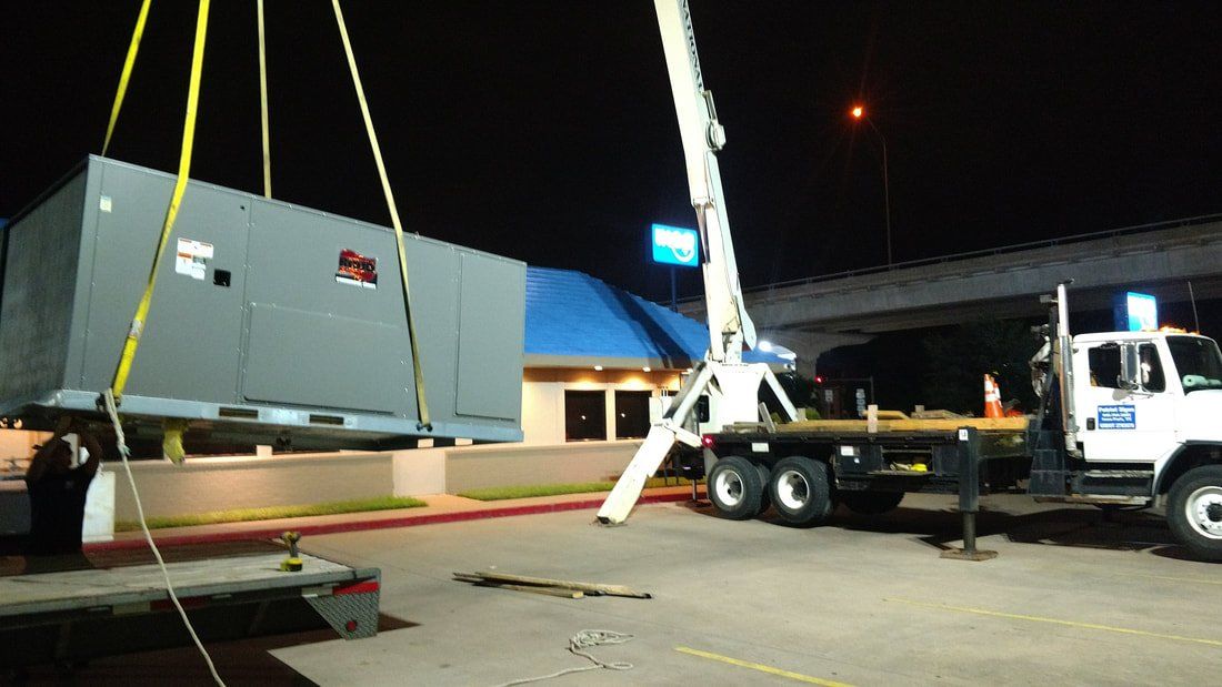 A large gray box is being lifted by a crane.