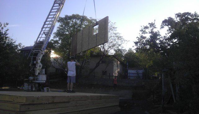 A crane is lifting a large piece of wood into the air