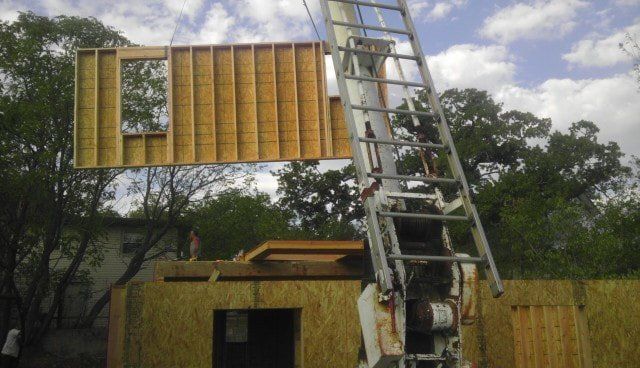 A ladder is being used to lift a large piece of wood