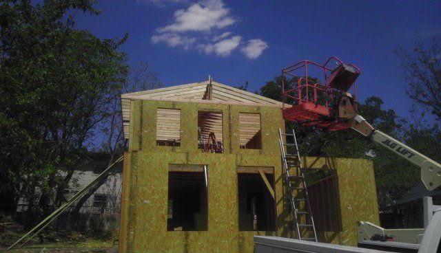 A house is being built with a crane on top of it.
