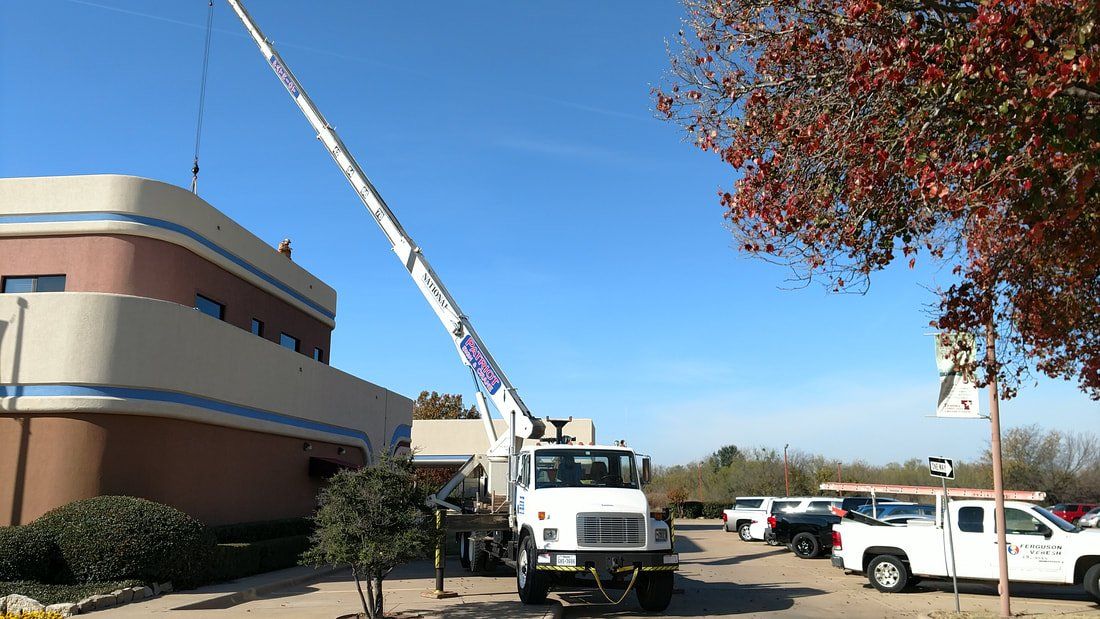 A truck with a crane attached to it is parked in front of a building.