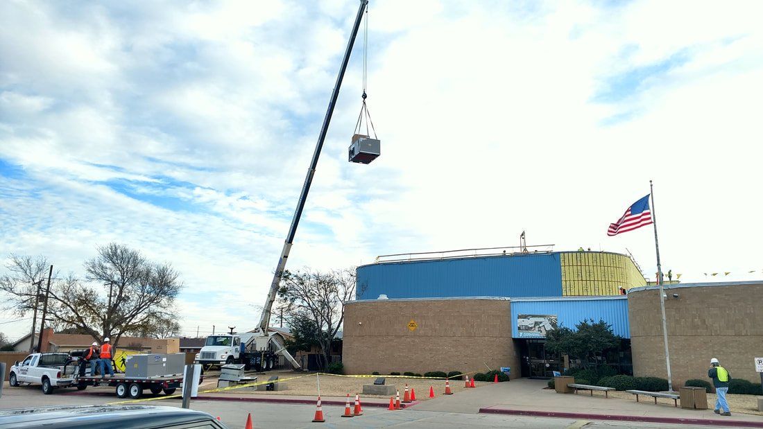 A crane is lifting a container in front of a building.