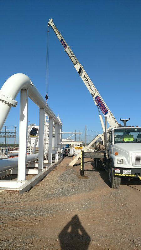 A truck with a crane attached to it is parked in front of a pipe.
