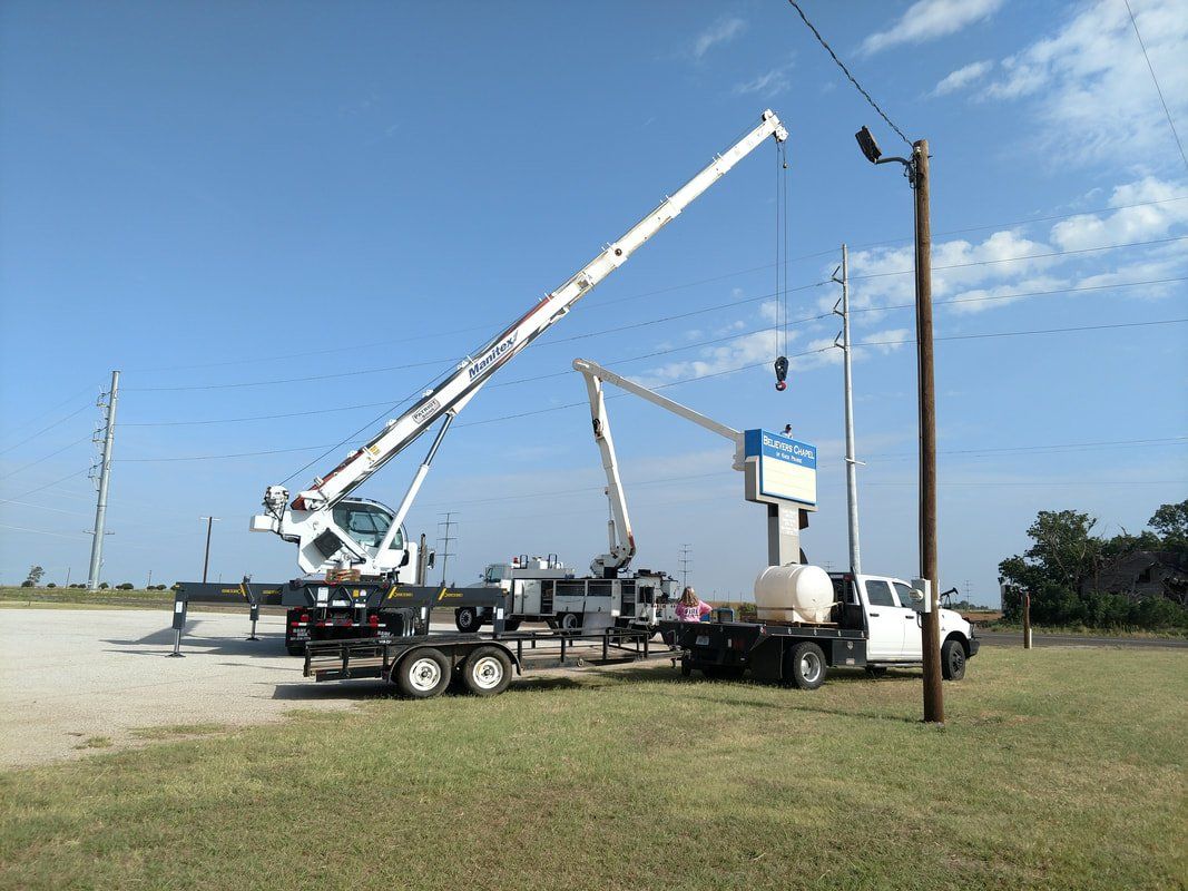 A truck with a crane attached to it is parked in a grassy field.