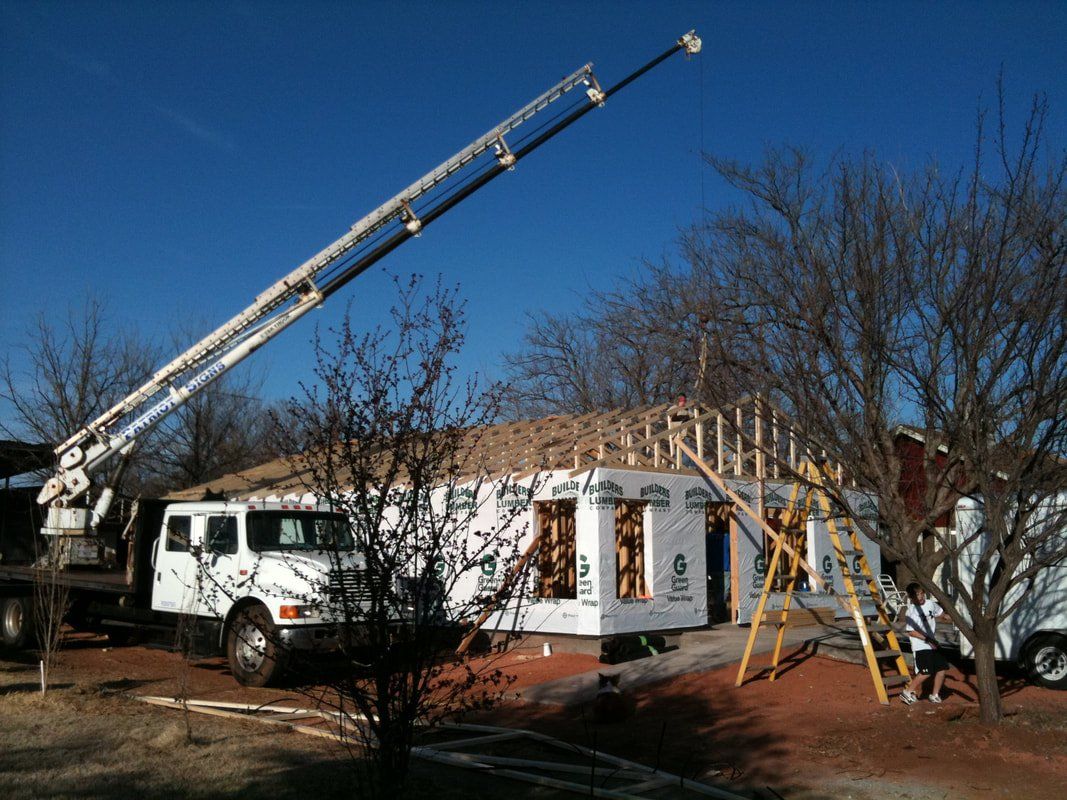 A white truck is parked in front of a house under construction.