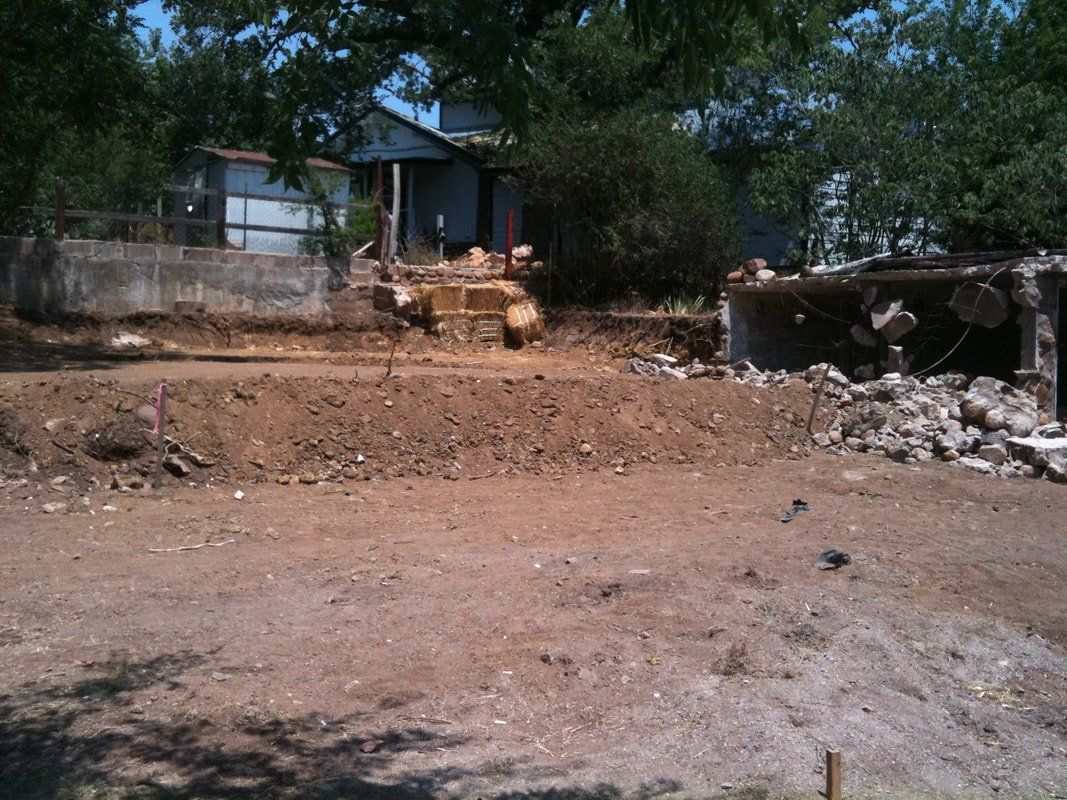 A dirt field with a house in the background