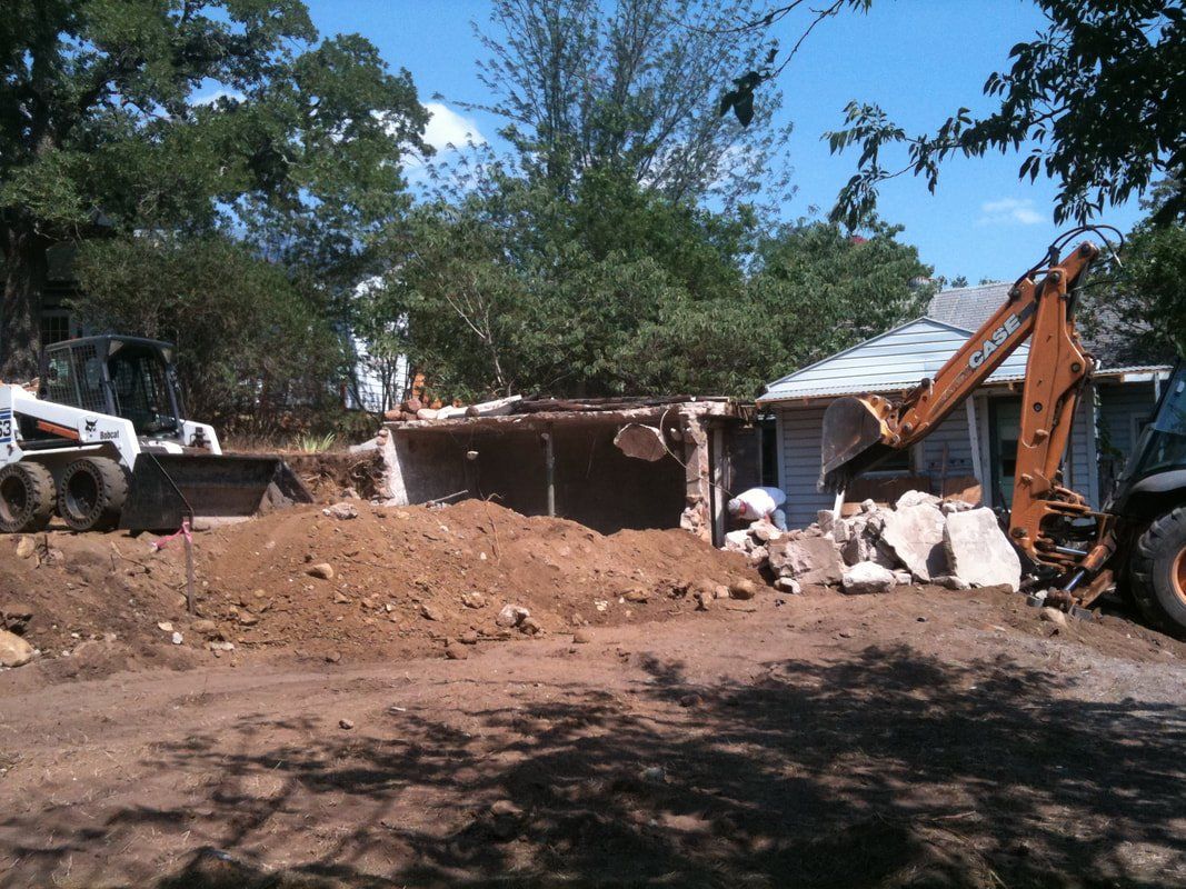 A house is being demolished by a bulldozer and a backhoe.