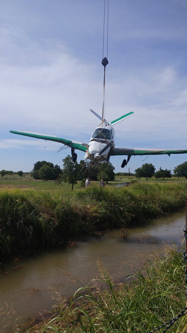 A small plane is being lifted over a body of water.