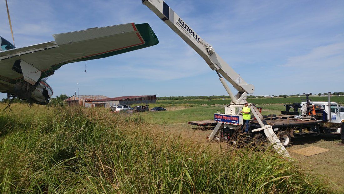A plane is being towed by a crane in a field.