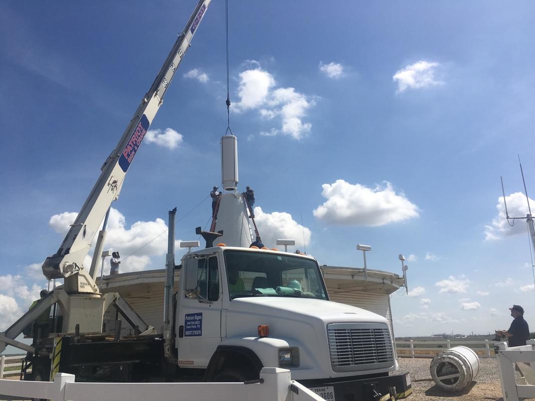 A white truck with a crane attached to it is parked in a field.
