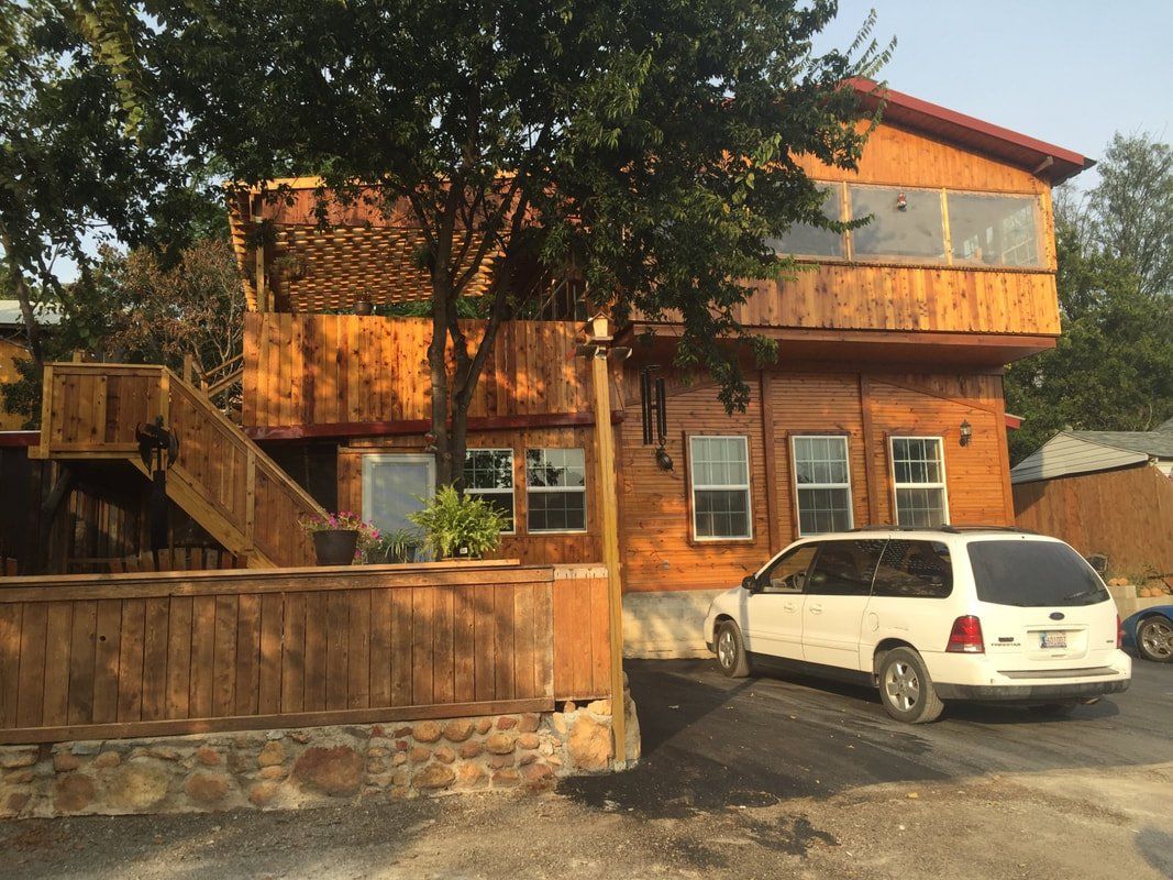 A white van is parked in front of a large wooden house.
