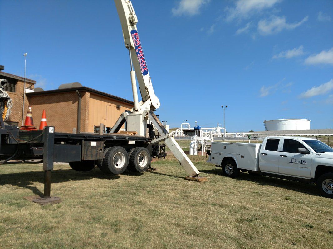 A white truck is parked next to a crane in a field.