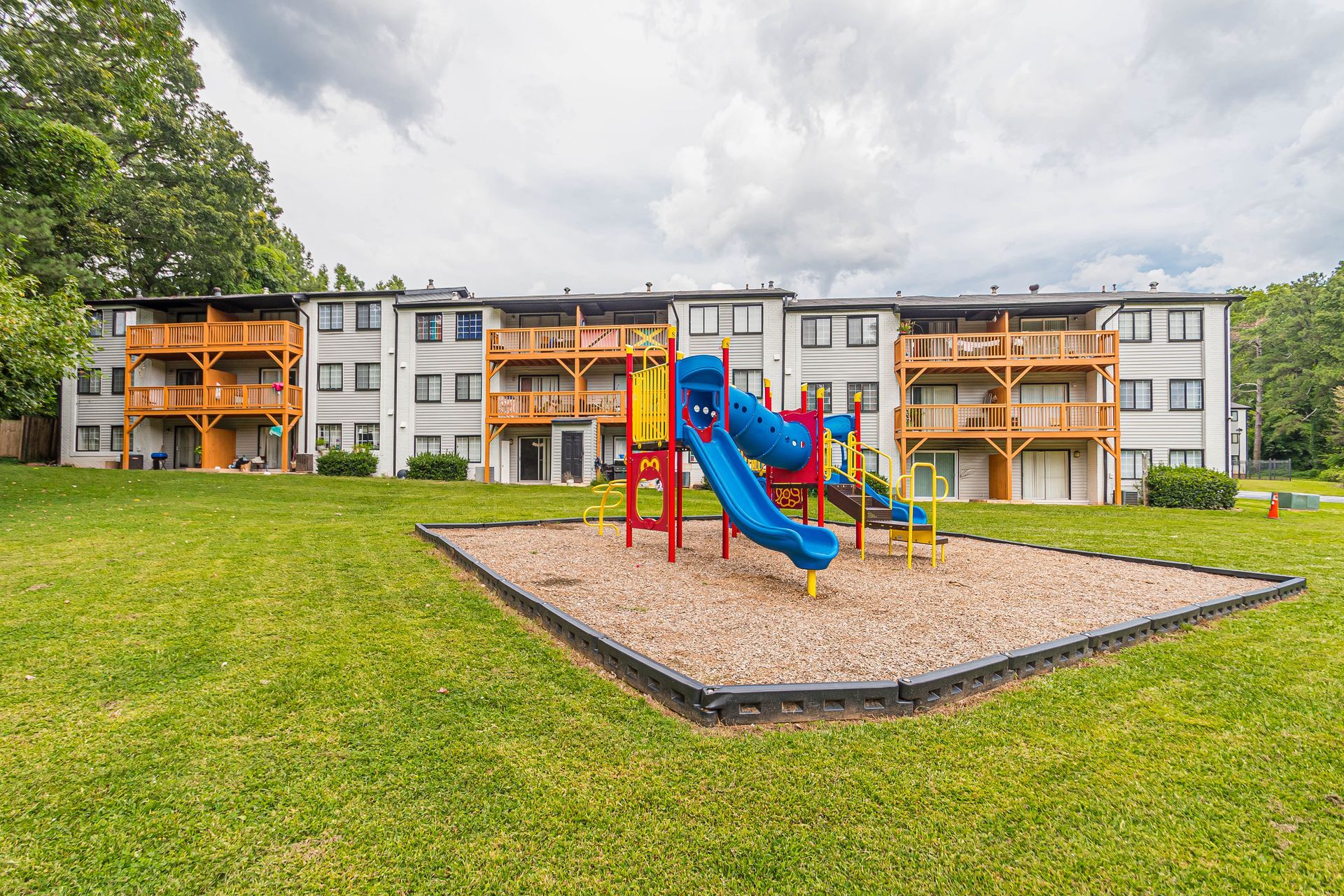 Apartment complex playground with colorful slide and climbing structure on a grassy lawn