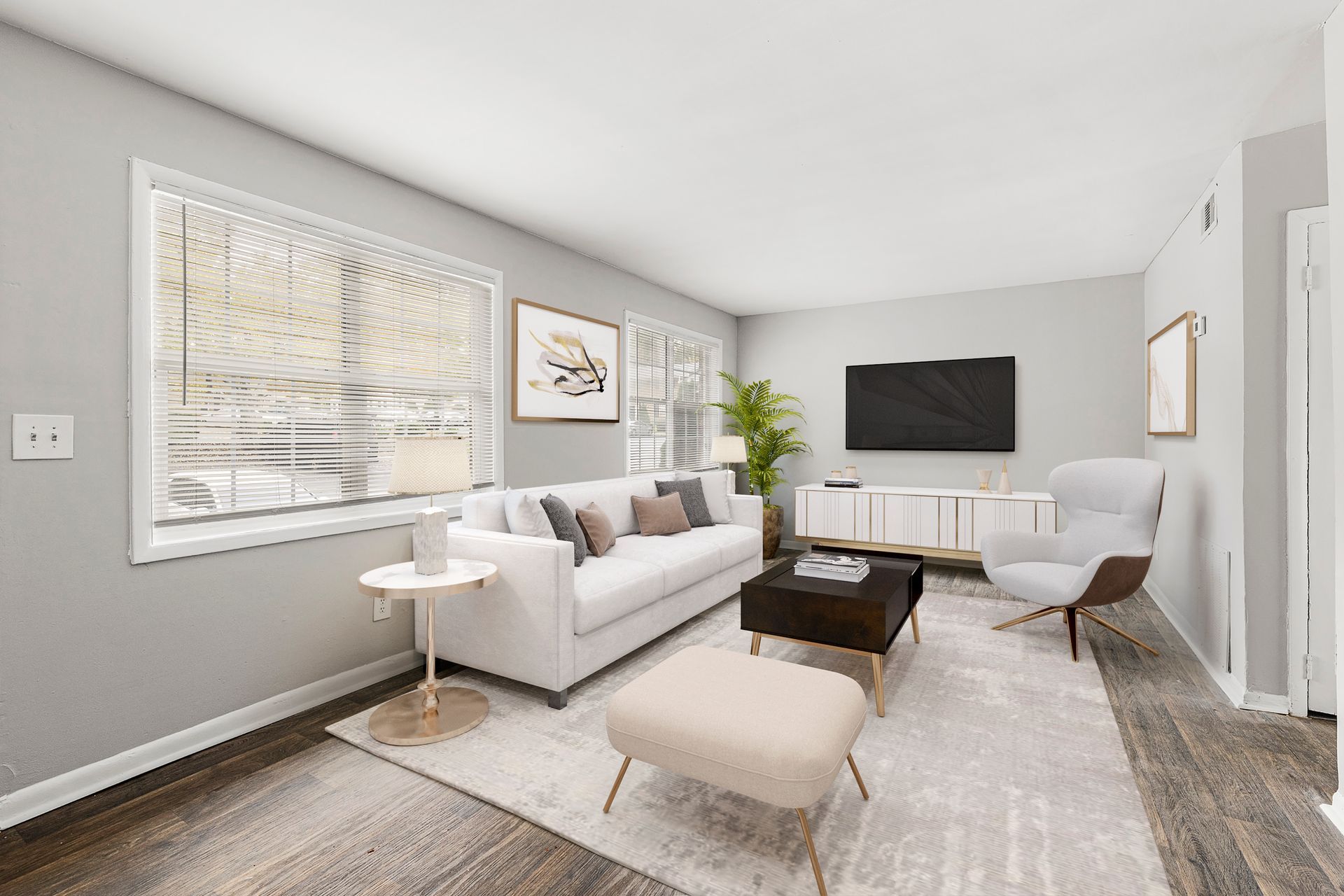 Modern gray living room with white sofa, armchairs, dark coffee table, wall-mounted TV, and large windows.