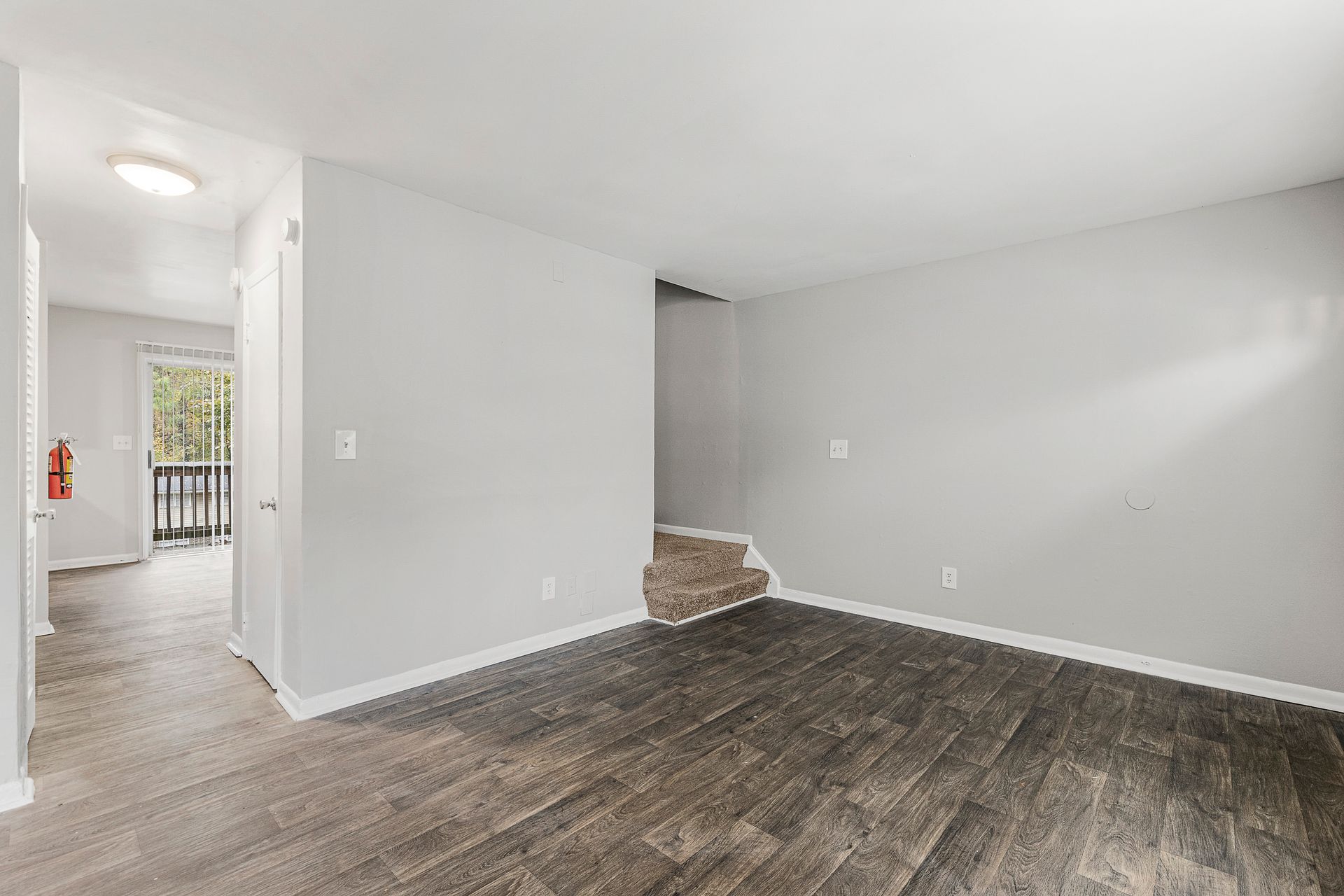 Empty living room with gray walls, wood-look floor, and a small step down near the back wall.