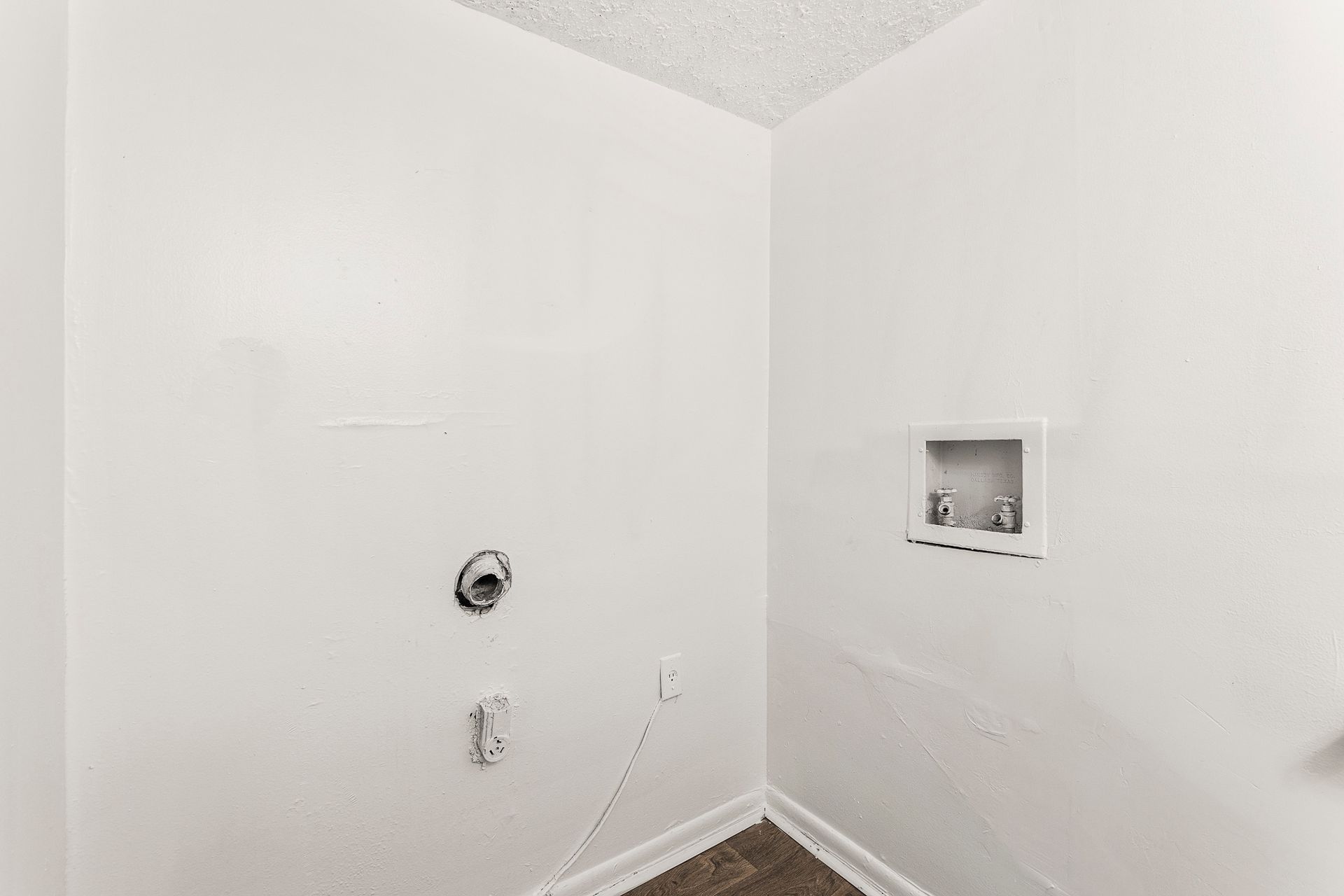 Empty white utility room with plumbing hookups and a recessed wall niche, likely for laundry or appliances