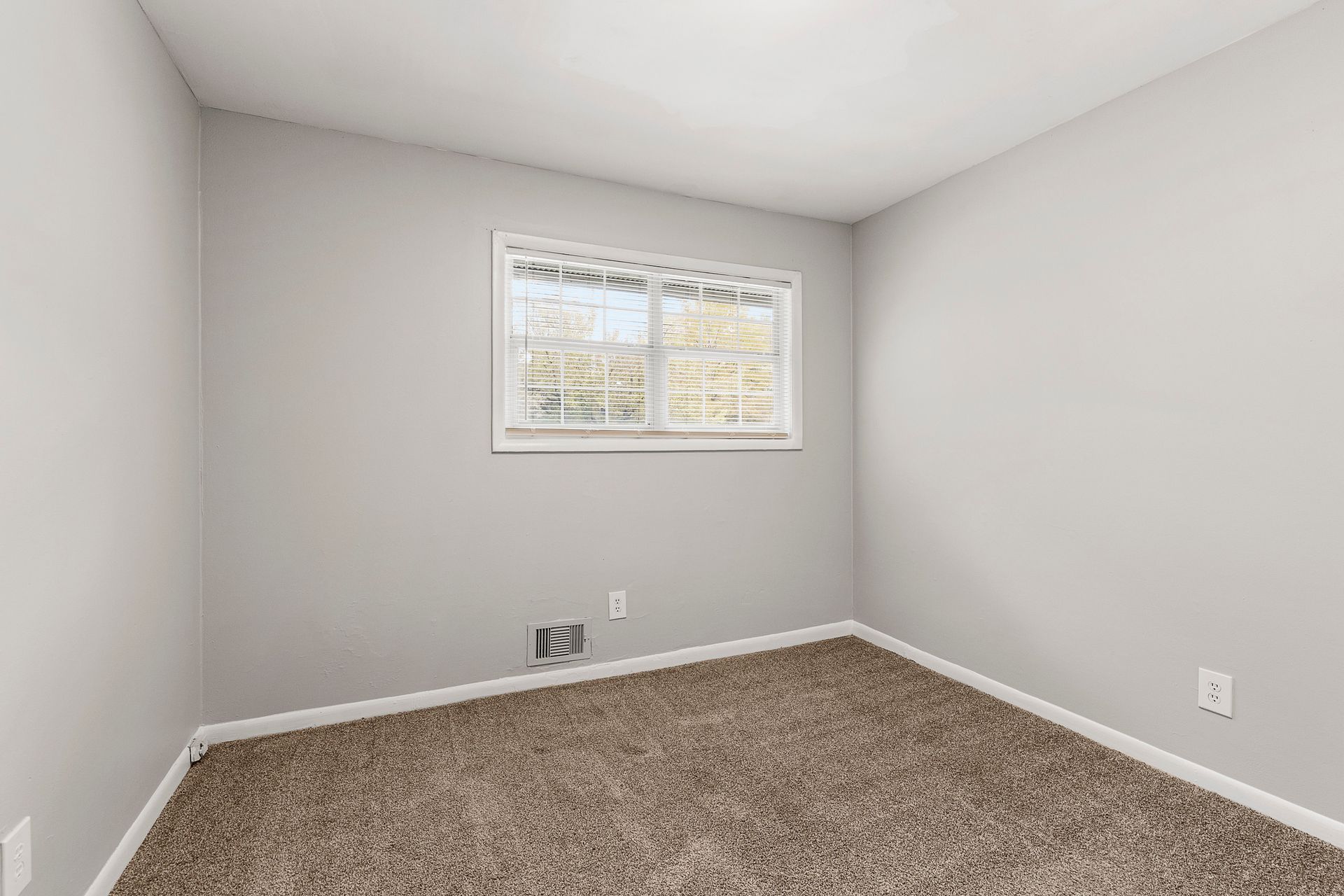 Empty gray bedroom with carpet and a small window