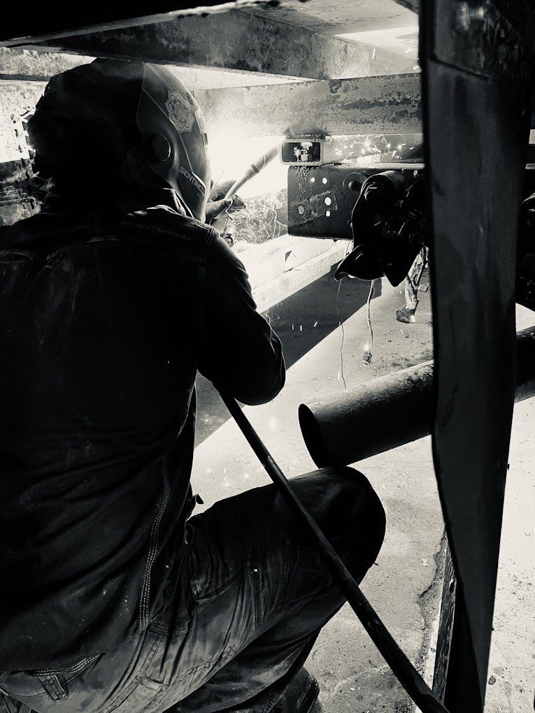 A black and white photo of a man welding a piece of metal
