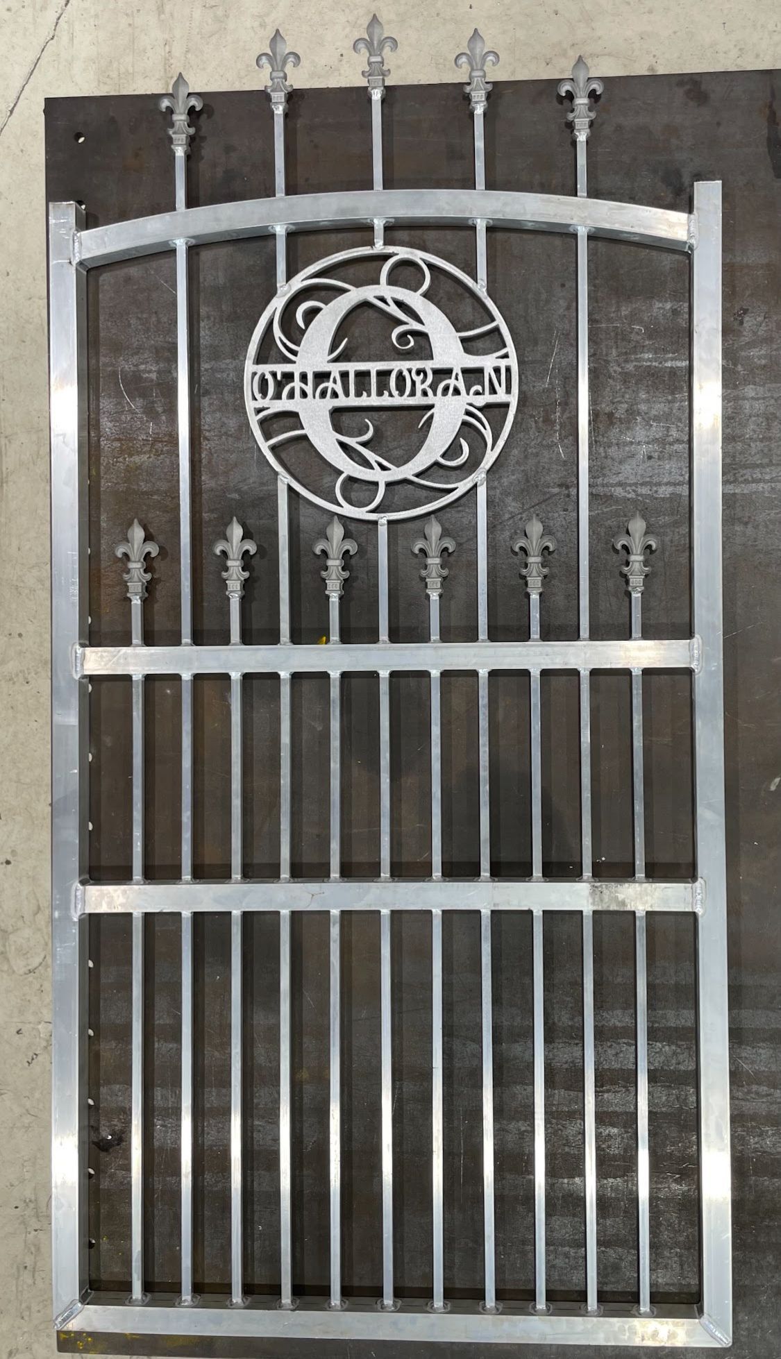 A metal gate with a monogram on it is sitting on top of a wooden table.