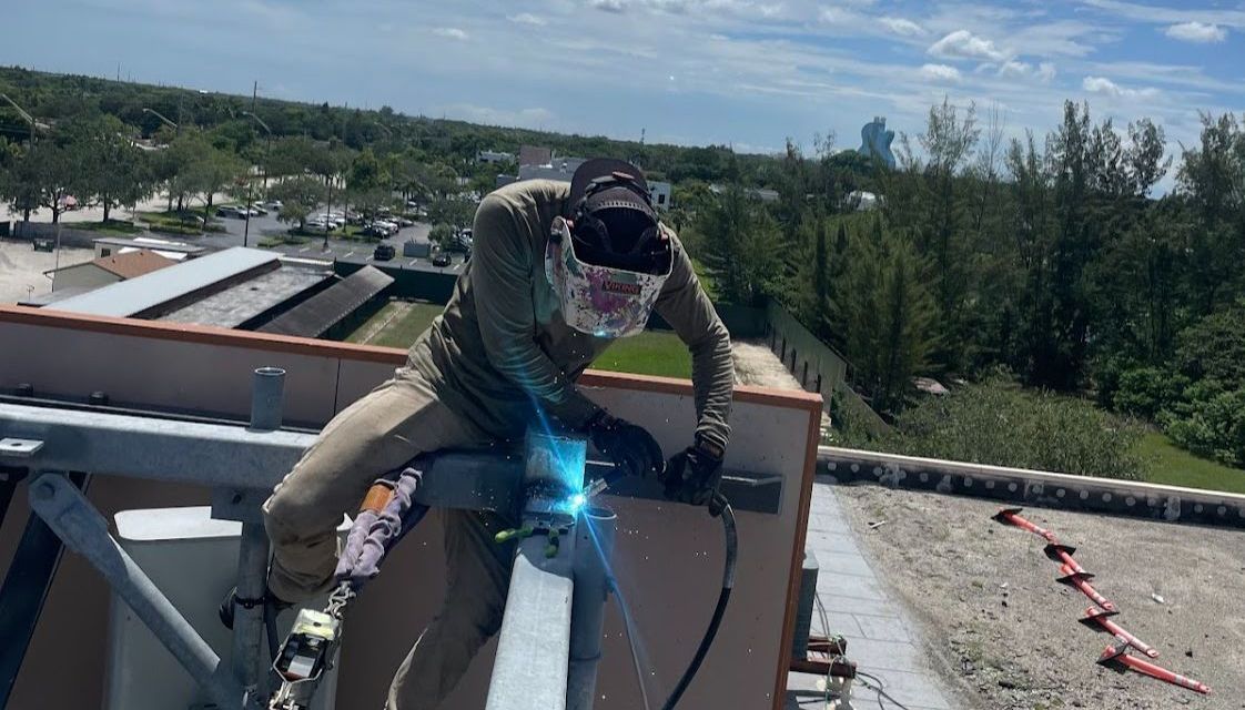 A man is welding on the roof of a building.