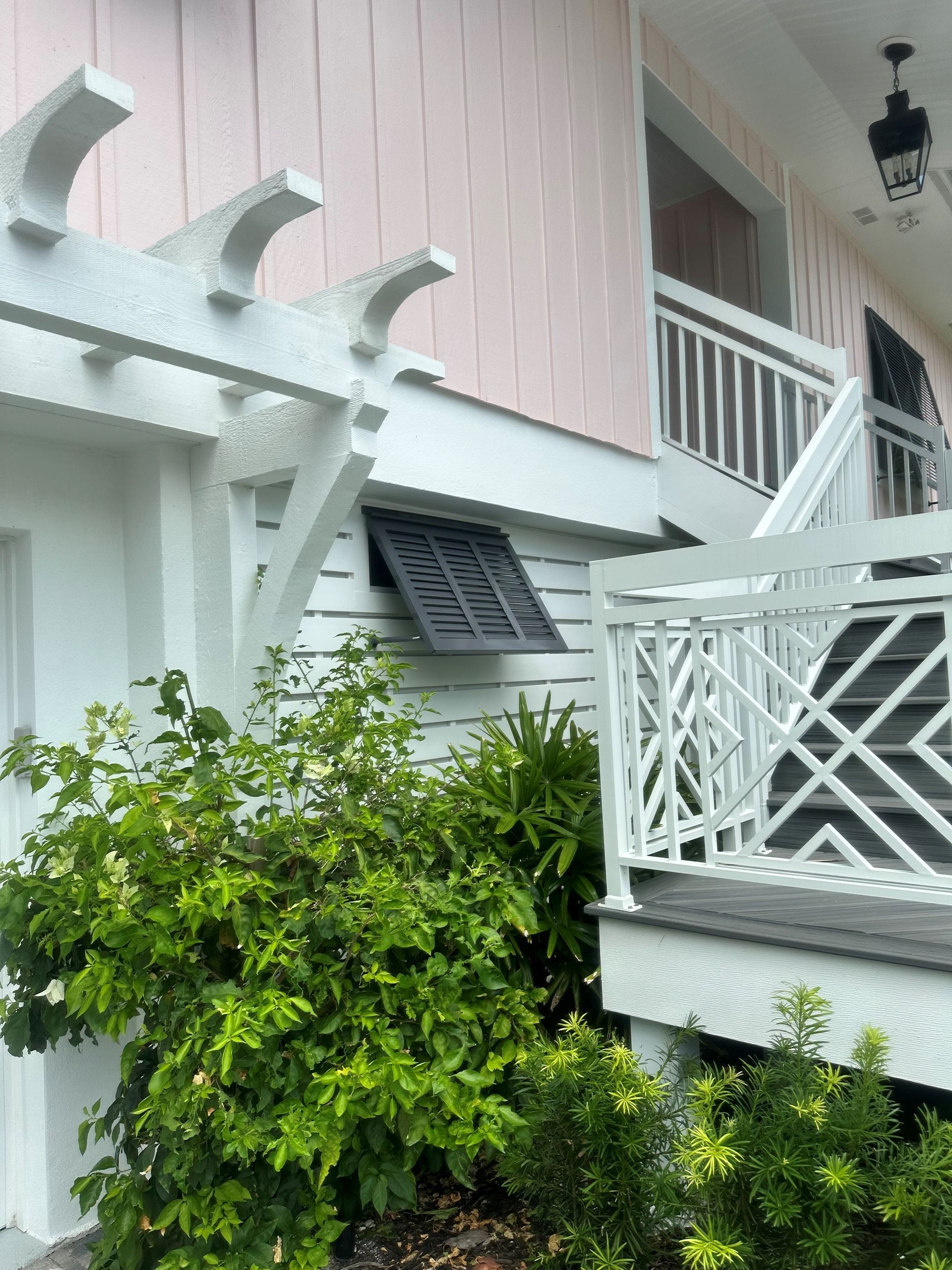 A white house with pink siding and a white pergola