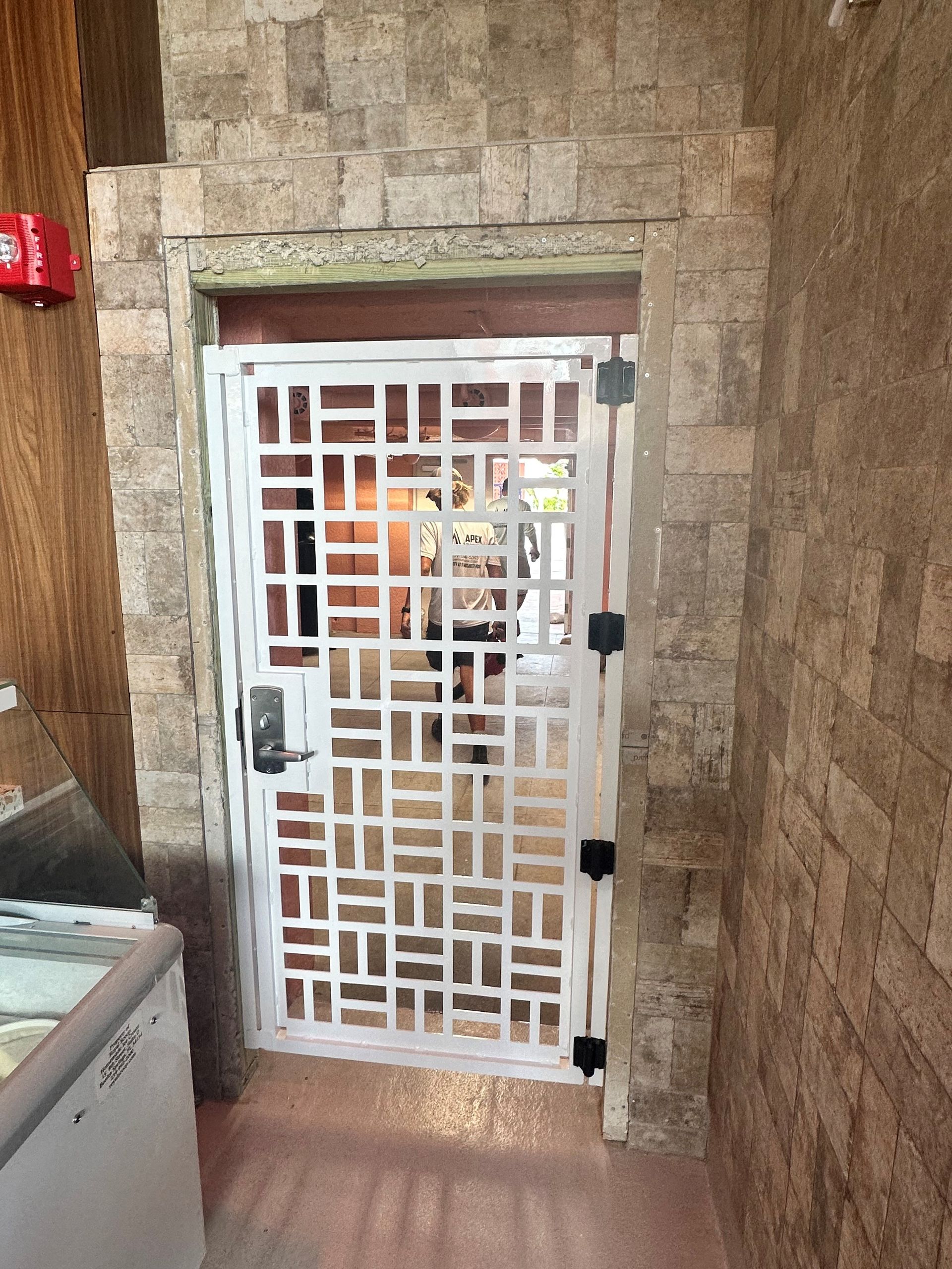 A white gate is between two brick walls in a room.