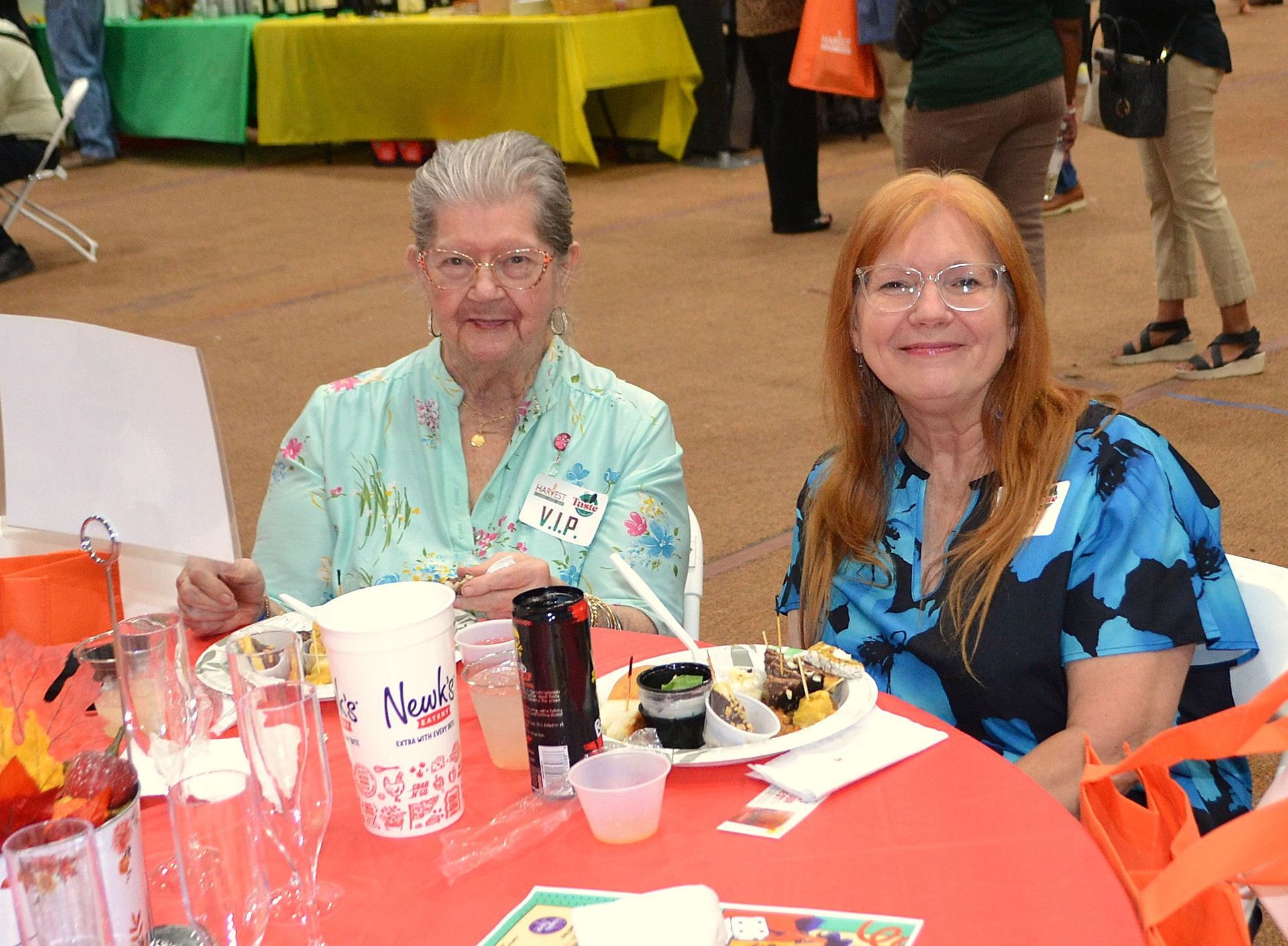 Two people seated at a table with drinks and food at an indoor gathering
