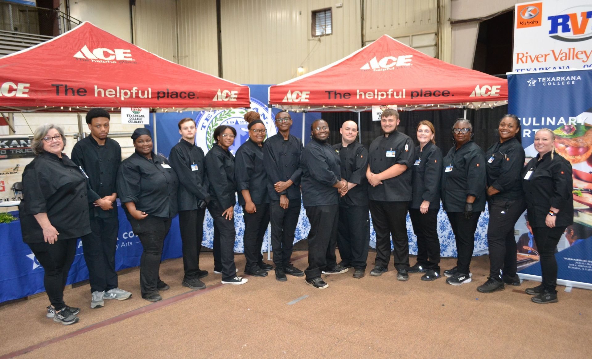 Group of uniformed workers posing under ACE tents at an outdoor event