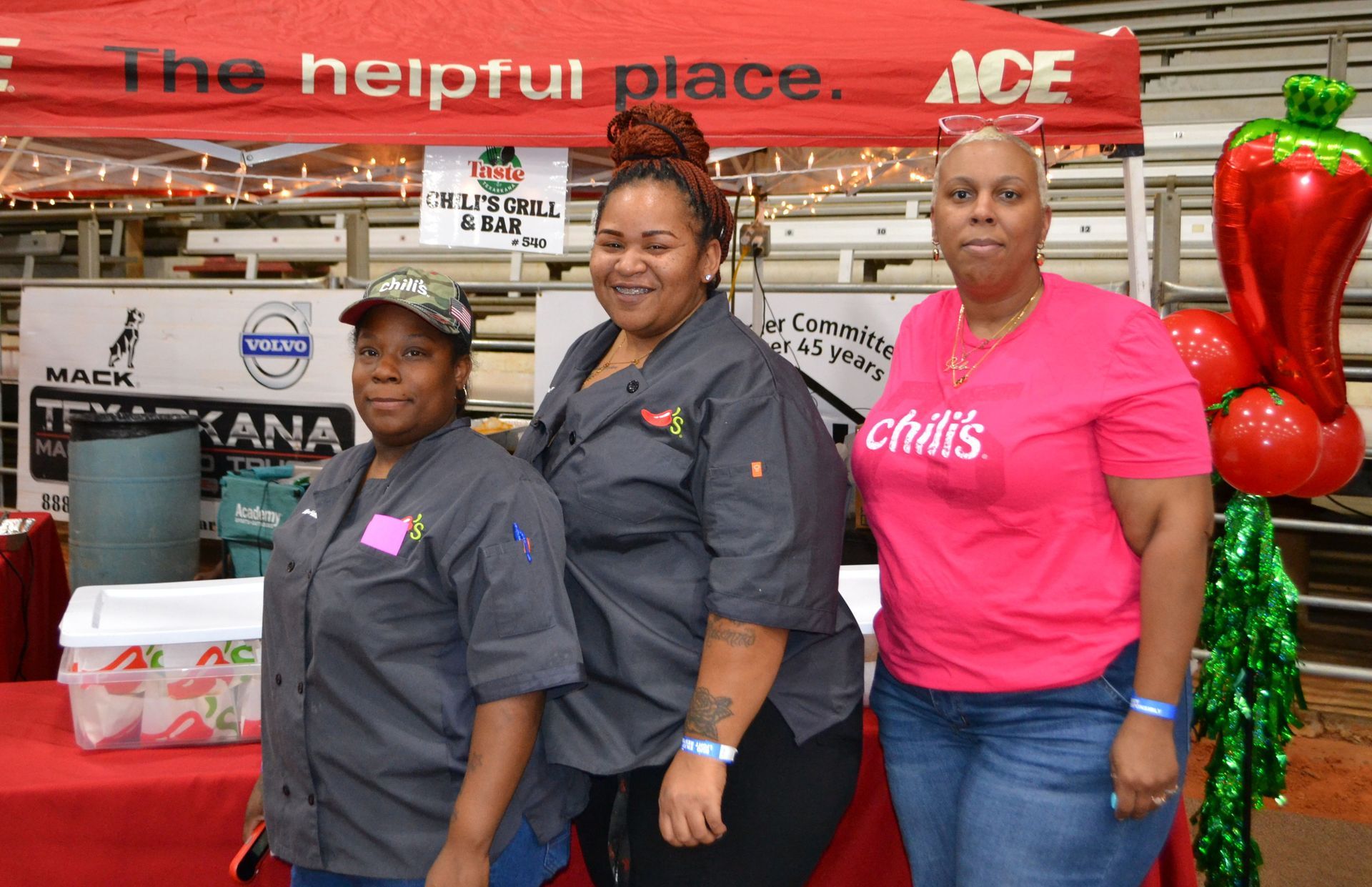 Three store employees in uniform stand behind a festive produce display under an ACE Market sign.