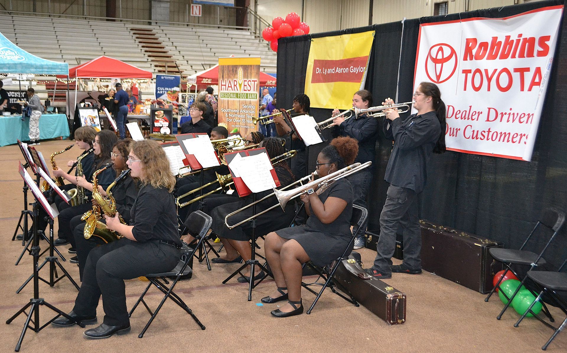 Street band performing outdoors beside a Robbins Toyota banner and red balloons.