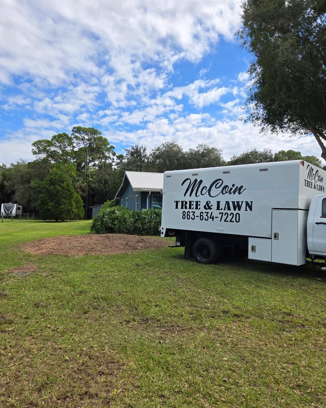McCain Tree & Lawn service truck parked on grass beside a green yard and cloudy blue sky