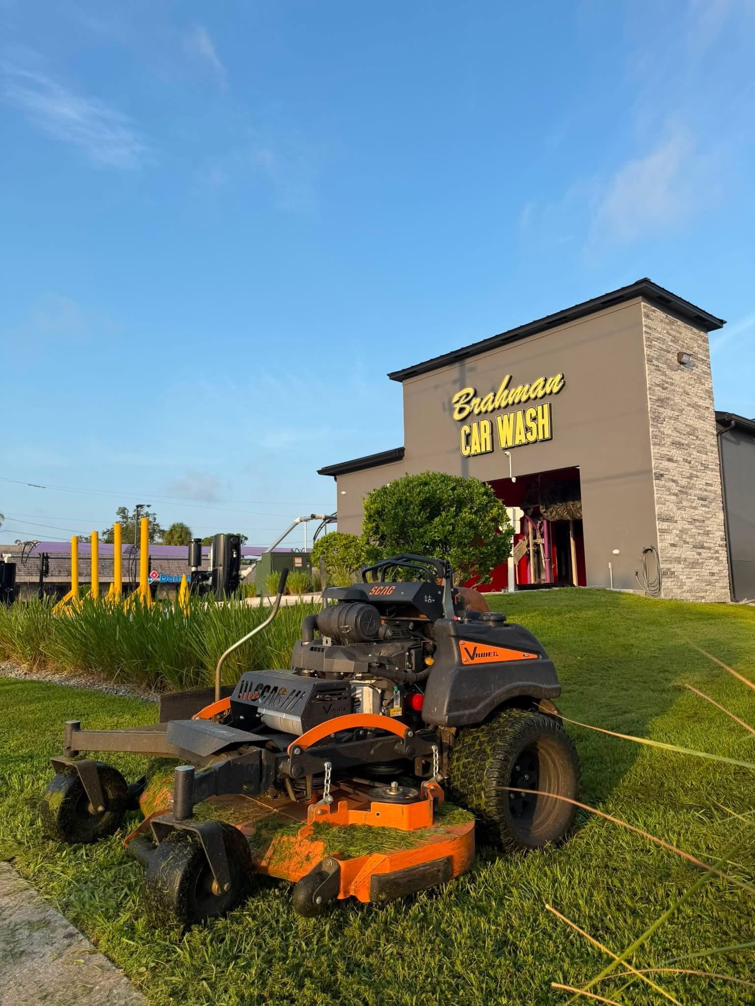 Lawn mower in front of a Salon & Spa building on a grassy hillside under a blue sky