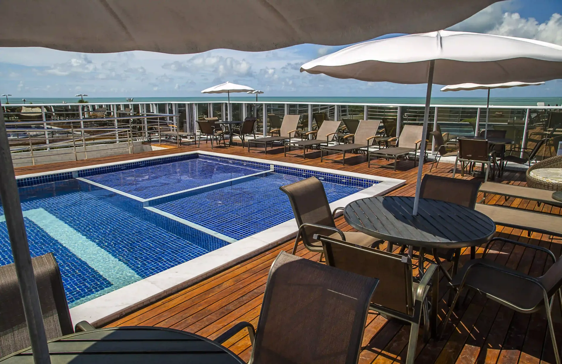 Uma grande piscina com mesas e cadeiras ao redor.laguna-praia-hotel