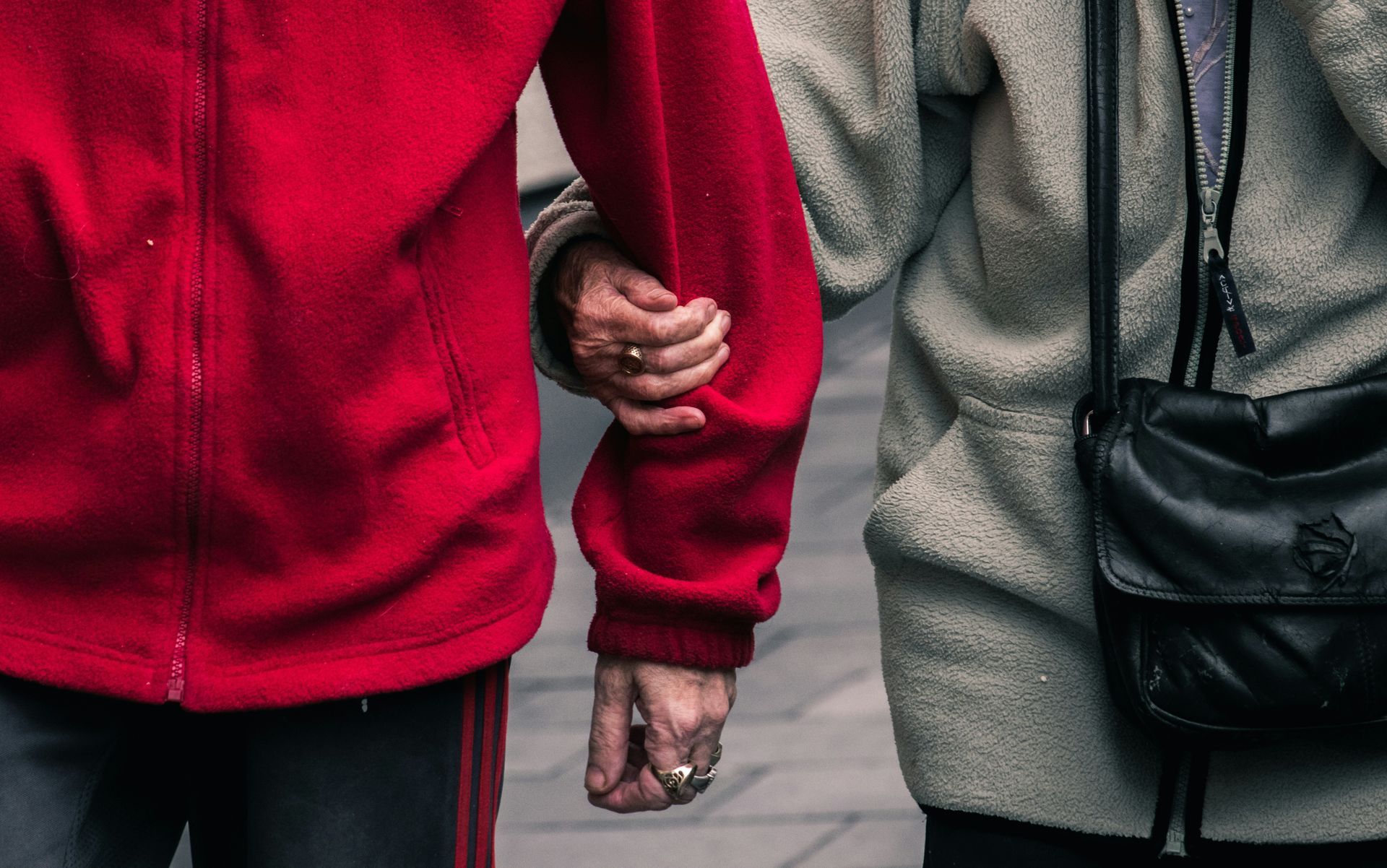 Two people are holding hands while walking down the street.