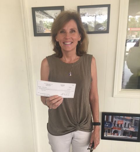 A woman is holding a check in her hand and smiling